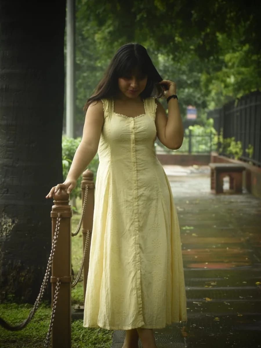 Young woman in a pale yellow midi dress, full length outdoor portrait