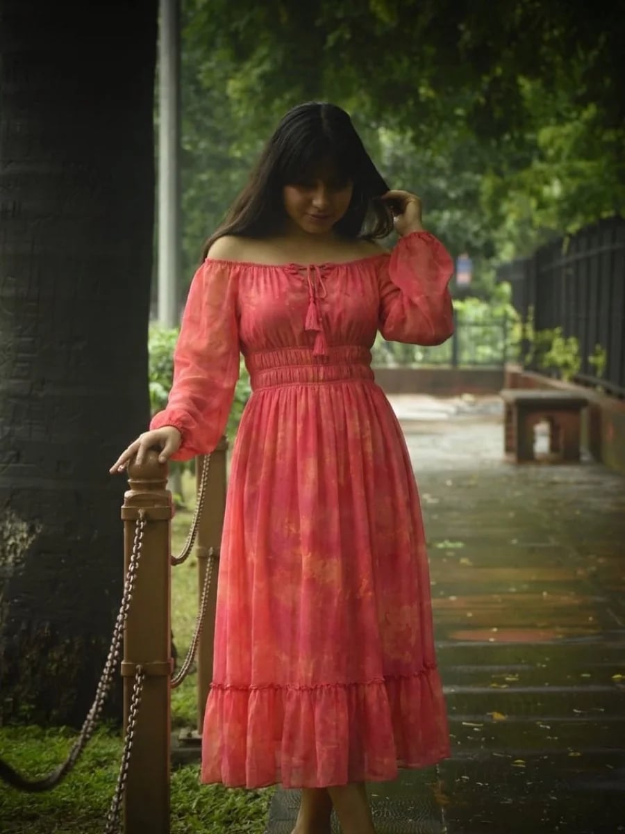 Young woman in a coral pink midi dress, full length outdoor portrait